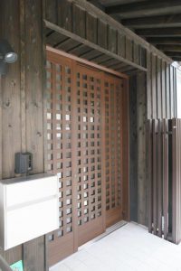 オーナー玄関は敢えて格子建具とし、縦張り杉板外壁や化粧垂木天井との程良い ハズし調和を図る